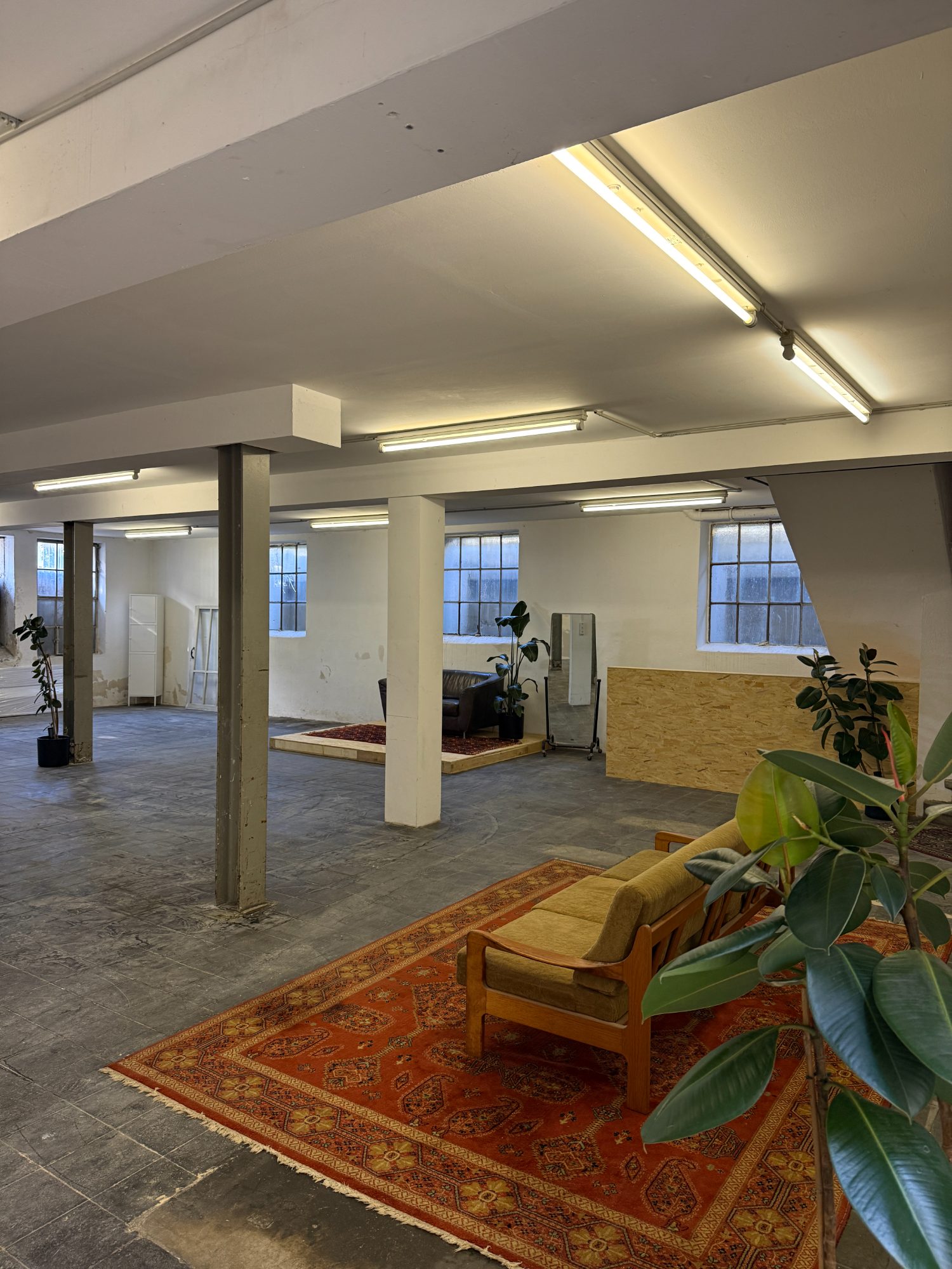 Das Loft: offene Halle mit Säulen, geschliffenem Boden, Lichtschächten, Teppichen und Pflanzen
