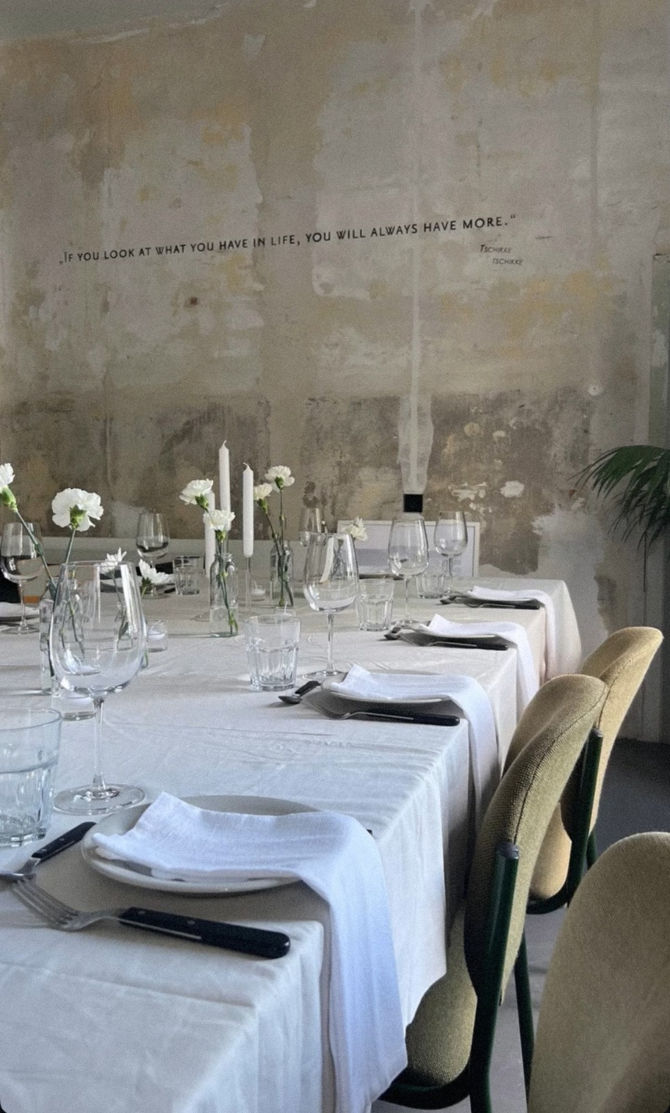 Gedeckte Tafel im WerDerRaum — Rohputz-Wand, Gläser und Blumen